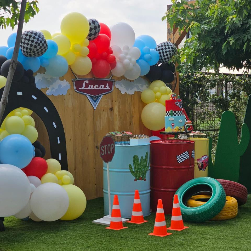 Decorative setup with balloons, cones, and car-themed props on a grassy area.