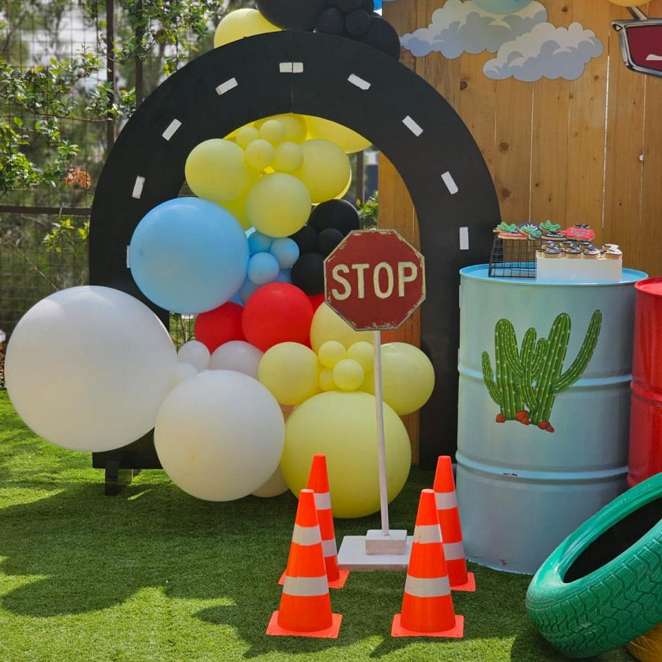 Children's birthday party setup with balloons, arch, and traffic-themed decorations.