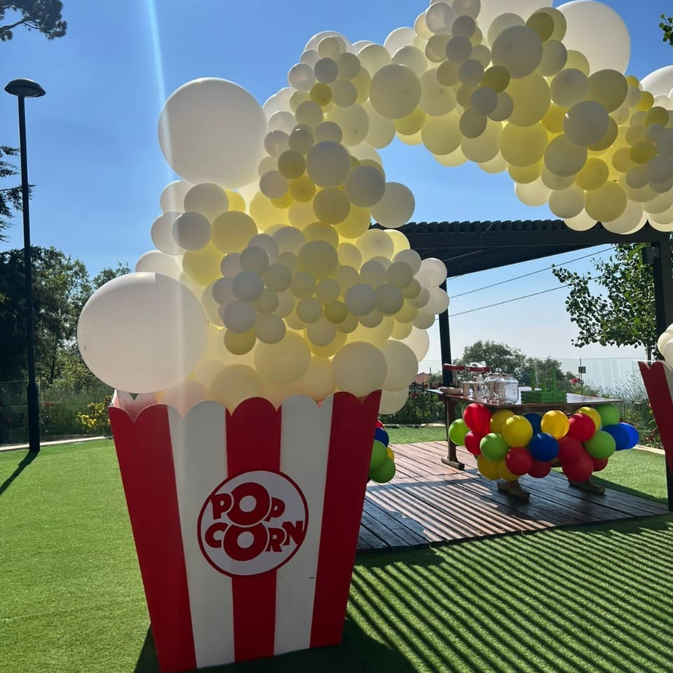 Balloon arch shaped like a popcorn bucket with a clear blue sky background
