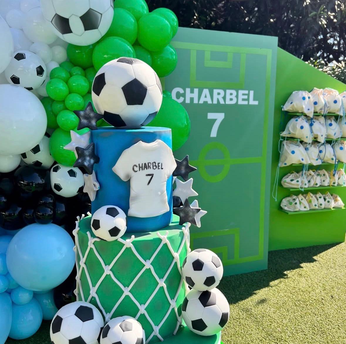 Soccer-themed birthday cake with balloons and decorations, featuring a jersey and number 7 on a green background.