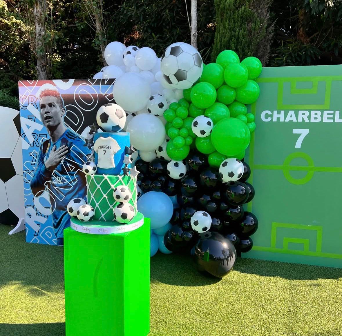 Decorative setup with soccer-themed balloons and a cake featuring a player, with 'Charbel' and number '7' visible.
