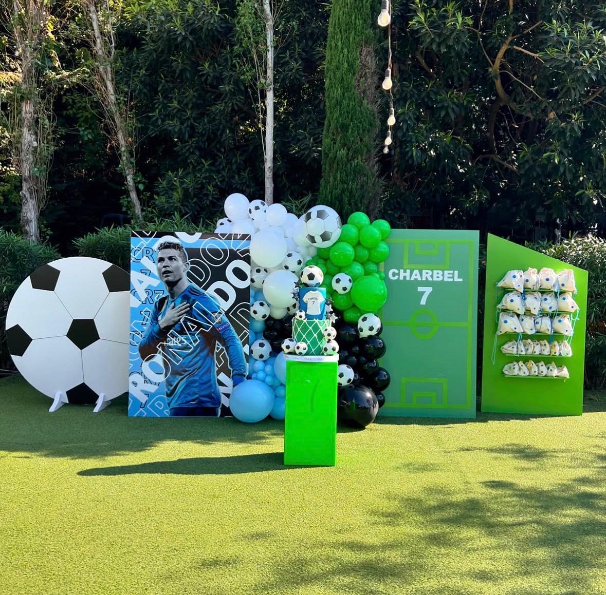 Decorative setup with soccer-themed balloons and props on a grassy area