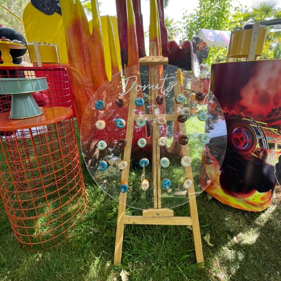 Colorful art installation with a transparent wheel and wooden stand on grass
