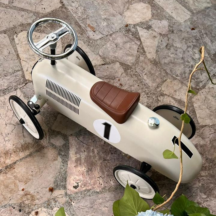 Vintage toy car on a stone surface with flowers and leaves.