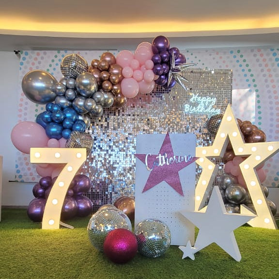 Decorative setup with balloons, stars, and numbers on a grass-like surface.