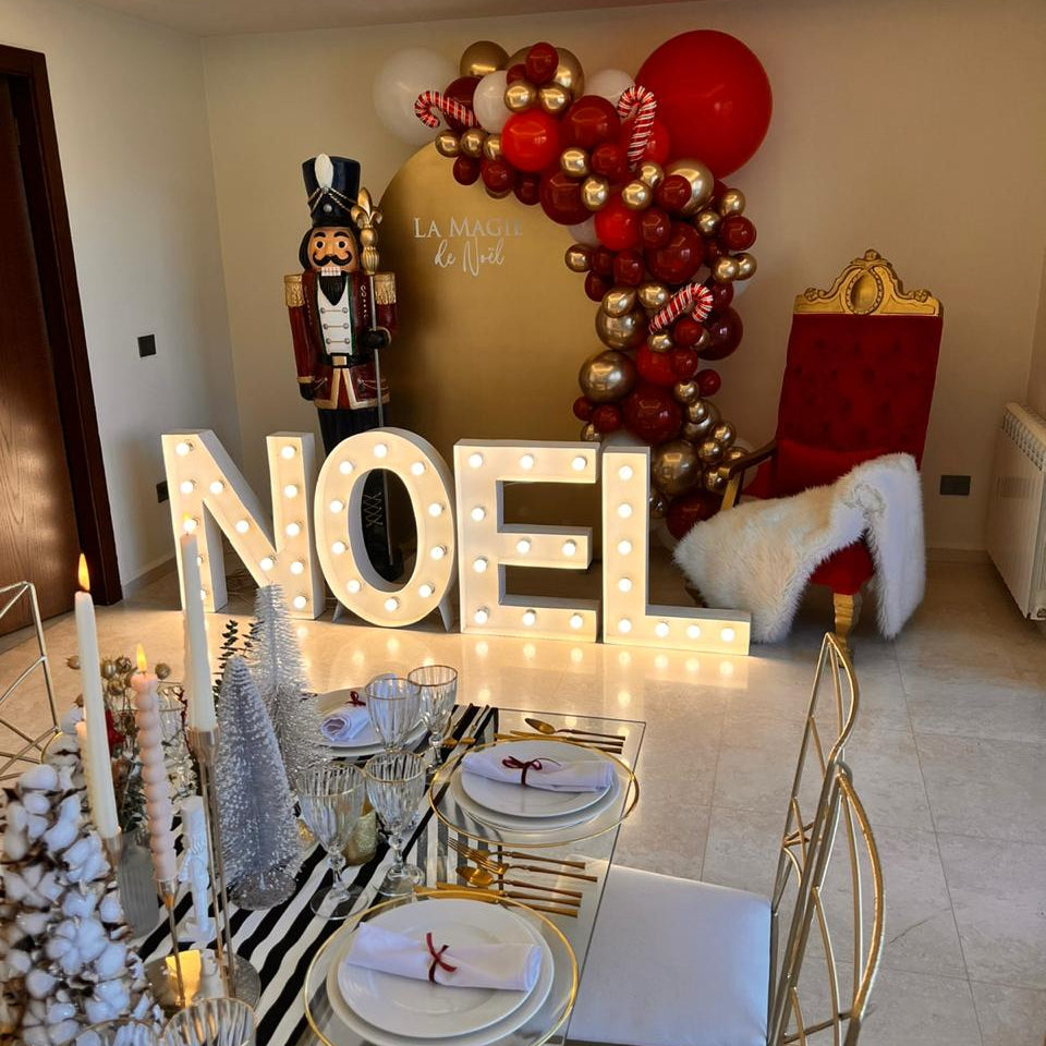 Decorated dining room with 'NOEL' sign, balloons, and Christmas-themed decor.