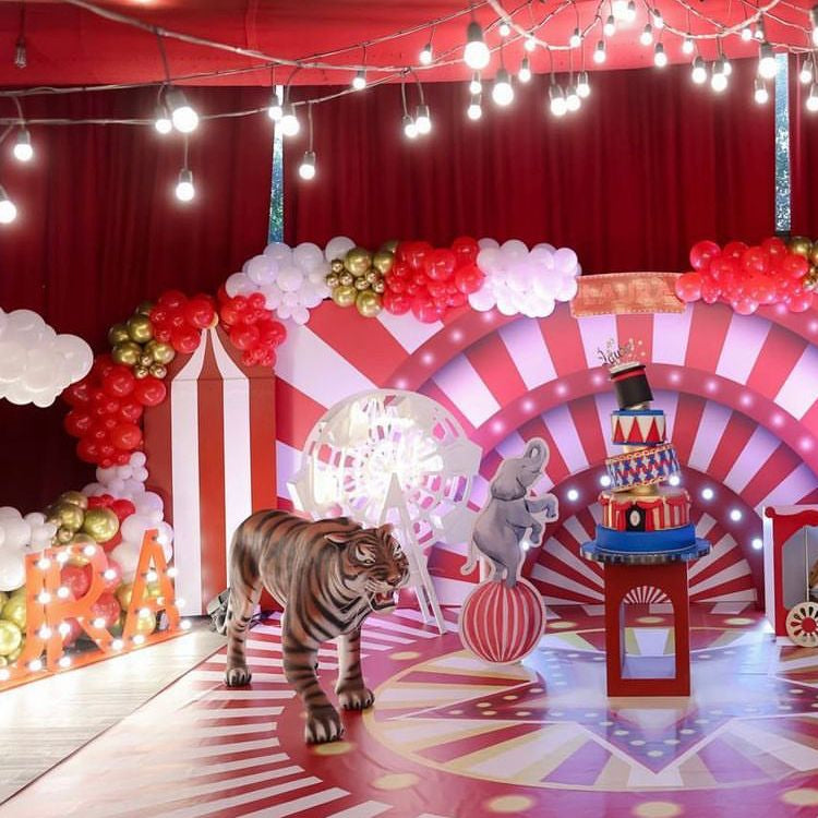 Carnival-themed decor with striped arch, balloons, and animal figures on a red and white floor.