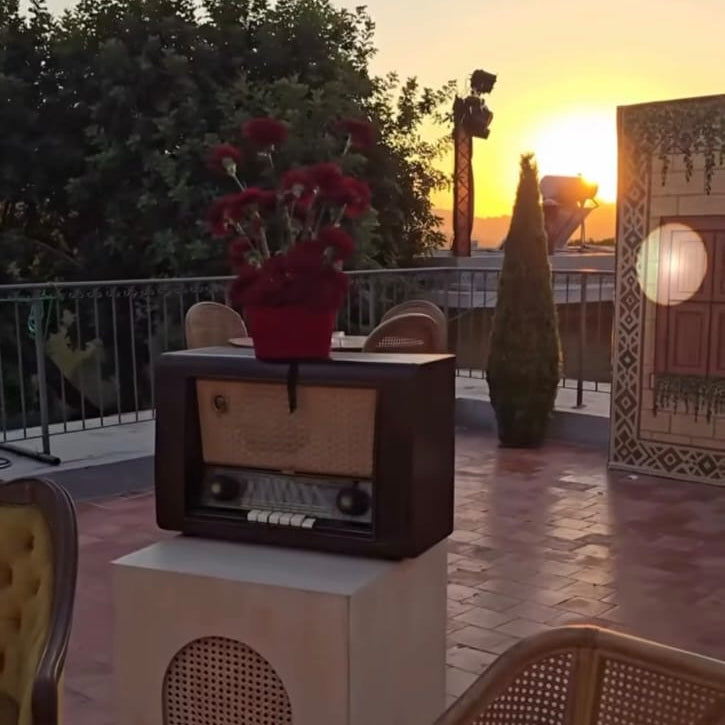 Vintage radio on a pedestal with a sunset in the background