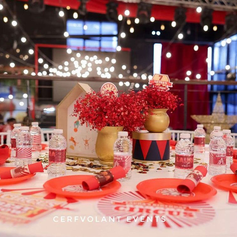 Decorated table with red plates, napkins, and centerpieces in a festive setting.