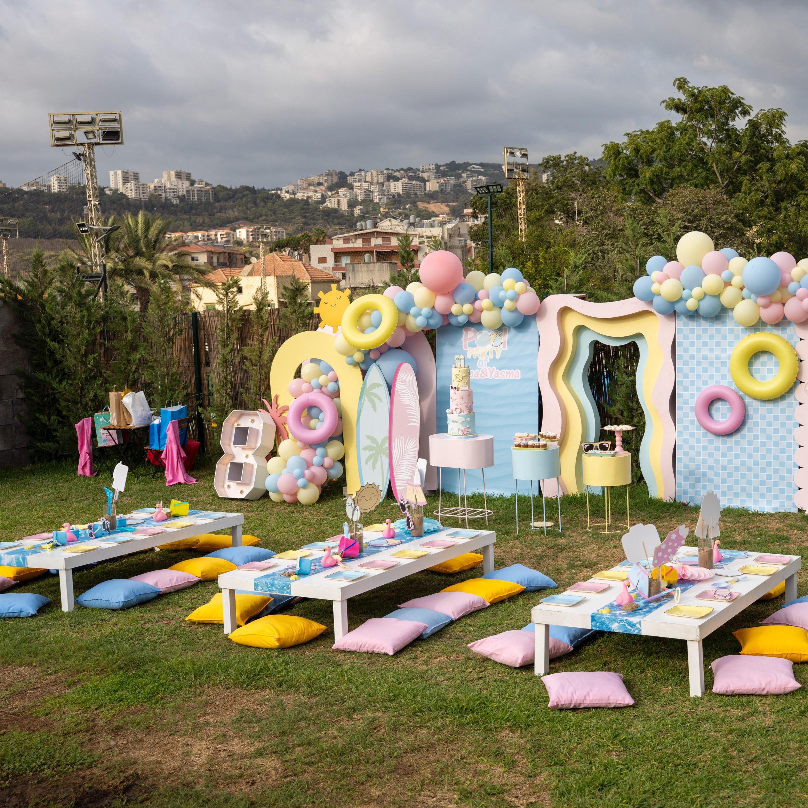 Decorative outdoor setup with balloons, props, and table settings for a celebration.