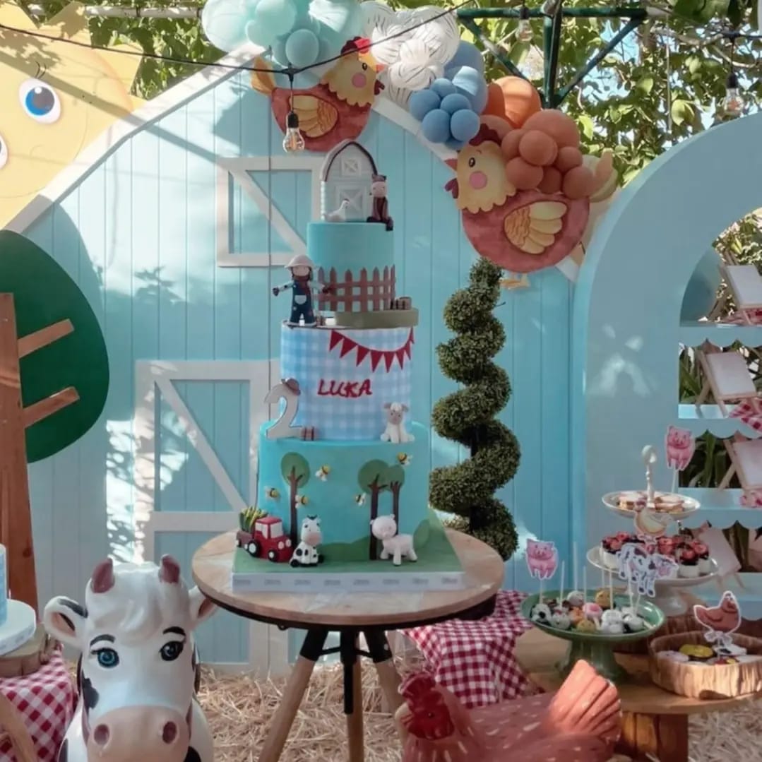 Children's birthday party setup with a cake, balloons, and decorations in an outdoor setting.