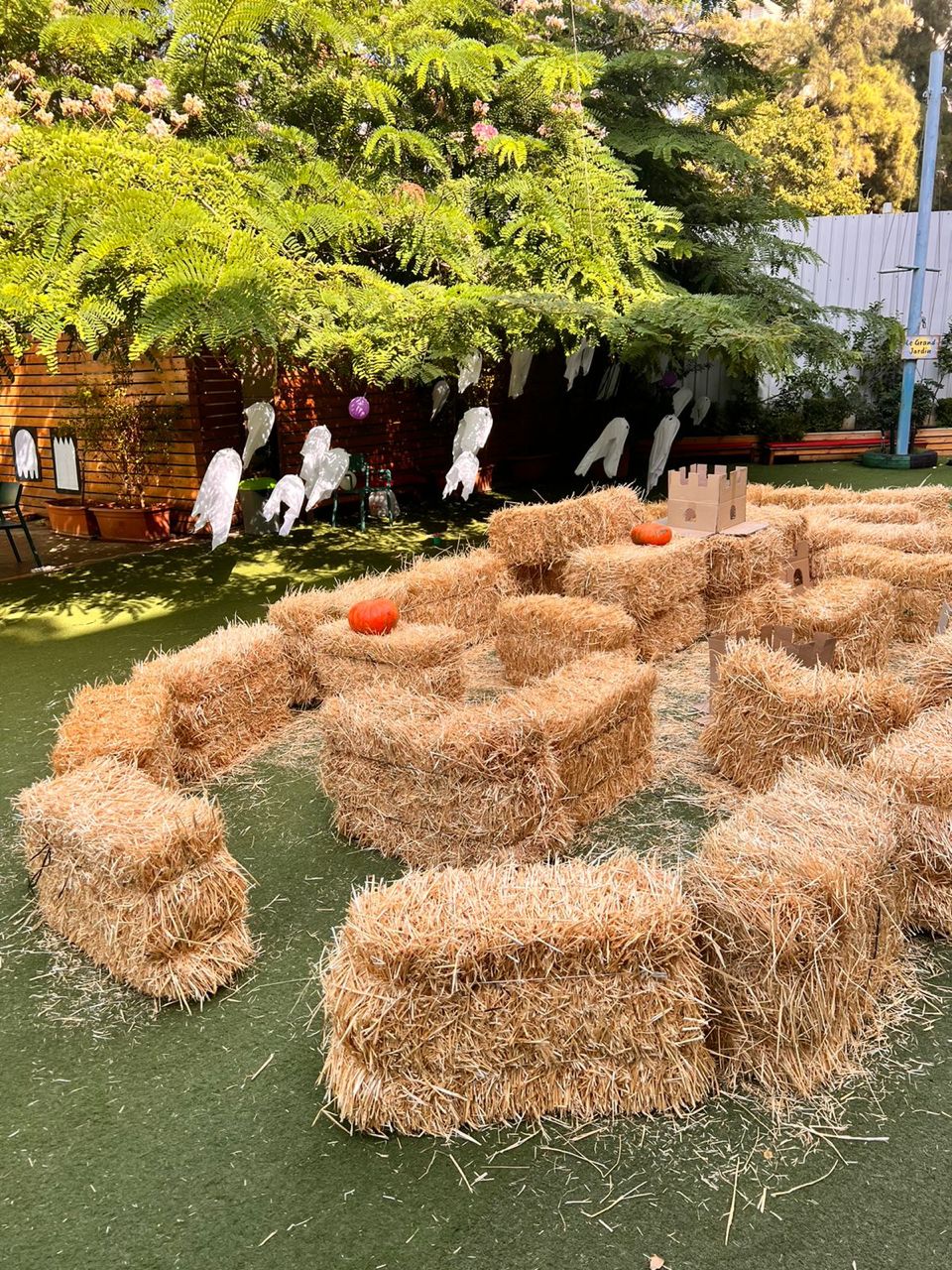 Hay bale maze with pumpkins and ghost decorations in an outdoor setting